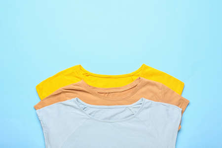 Different t-shirts on blue background, closeup