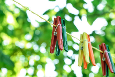 Colorful plastic clothespins hanging on rope outdoors, closeupの写真素材