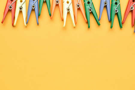 Many plastic clothes pins on color background, closeup