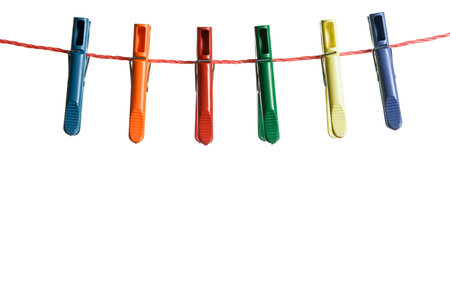 Colorful clothespins hanging on rope against white backgroundの写真素材