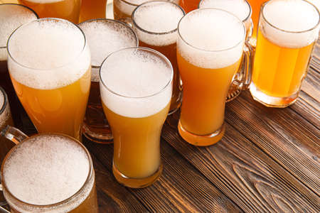 Mugs and glasses of cold beer on wooden background. Oktoberfest celebration