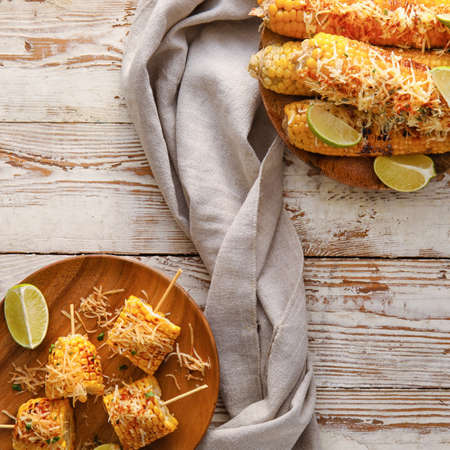 Plates with pieces of delicious Elote Mexican Street Corn on white wooden background
