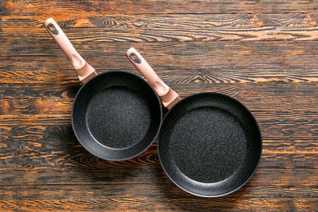 New frying pans on wooden backgroundの写真素材