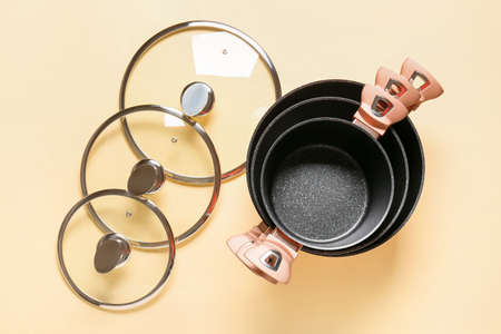 Cooking pots and lids on color background