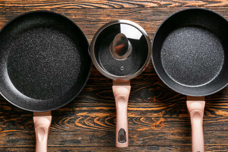 Frying pans and saucepan on wooden backgroundの写真素材