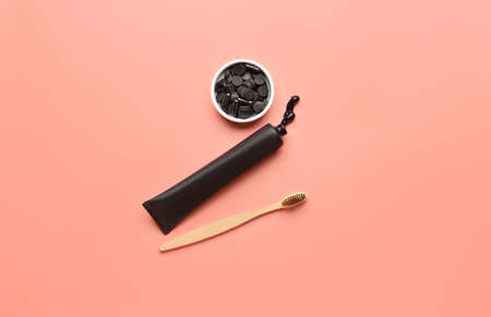 Bowl with activated charcoal tooth powder, toothpaste tube and toothbrush on color background