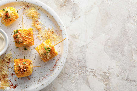 Plate with pieces of delicious Elote Mexican Street Corn on light background, closeup