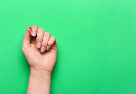 Female hand with gentle manicure on green backgroundの写真素材