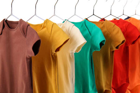 Different baby bodysuits hanging on white background, closeup