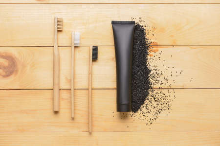 Black toothpaste with activated carbon and brushes on wooden backgroundの写真素材