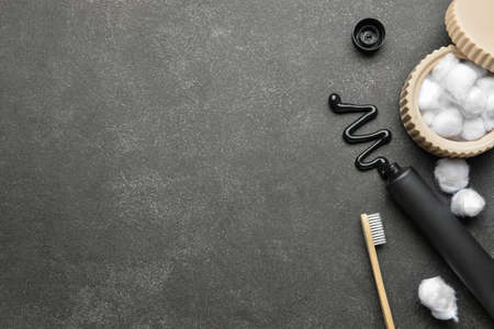 Black toothpaste with activated carbon, brush and cotton balls on dark backgroundの写真素材