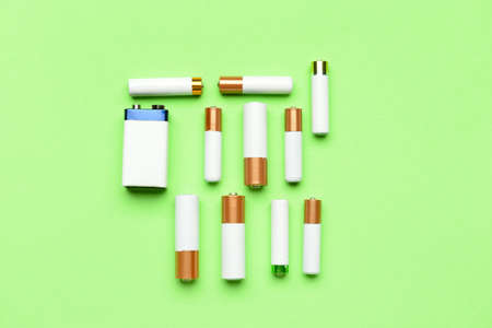 Different alkaline batteries on green background