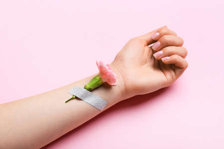 Female hand with beautiful manicure and taped carnation flower on color background