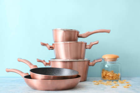 Set of copper kitchen utensils and jar with raw pasta on table against blue backgroundの写真素材