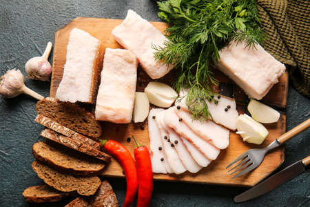 Wooden board with salted lard and bread on dark backgroundの写真素材