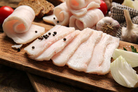 Board with slices of salted lard on wooden backgroundの写真素材