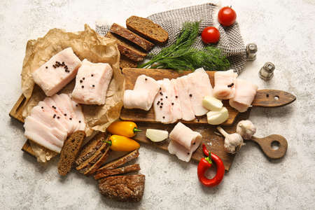Wooden boards with salted lard and bread on light backgroundの写真素材