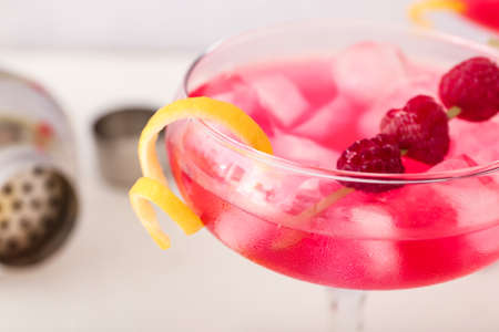Glass of tasty cosmopolitan cocktail on light background, closeup