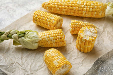 Fresh corn cobs and parchment on table, closeup