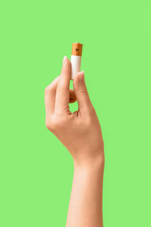 Woman holding alkaline battery on green backgroundの写真素材