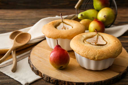 Board with tasty pear pot pies and fresh fruits on wooden background