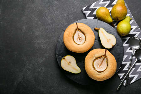 Wooden board with tasty pear pot pies and fresh fruits on dark backgroundの写真素材
