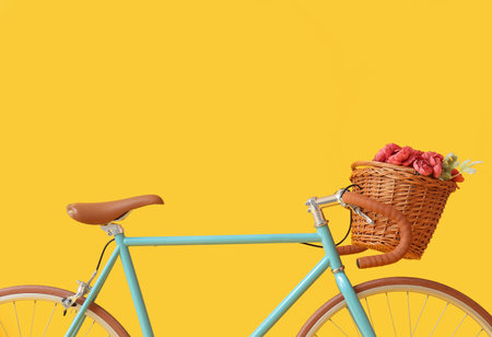 Modern bicycle with wicker basket and peony flowers on yellow backgroundの写真素材