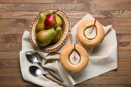 Tasty pear pot pies and fresh fruits on wooden background
