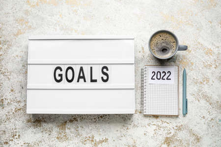 Board with word GOALS, notebook with figure 2022 and cup of coffee on grunge backgroundの写真素材