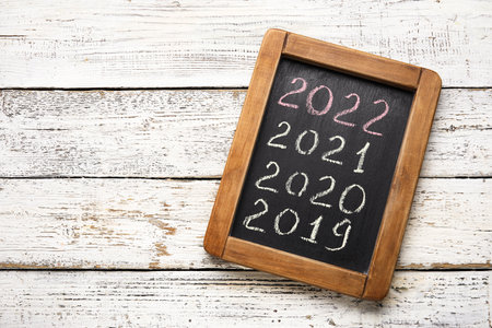 Figures denoting years 2019-2022 on chalkboard against white wooden backgroundの写真素材