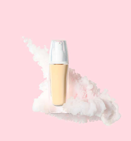 Bottle of makeup foundation in white smoke on pink background