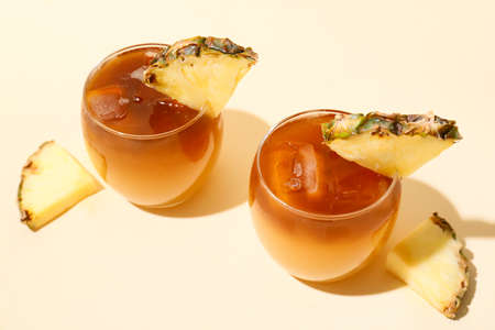 Glasses with delicious mai tai cocktail and pineapple slices on light table