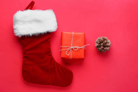 Gift box and Santa Claus stocking on red background