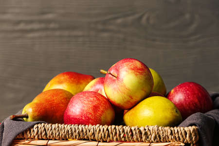 Box with ripe pears and apples on color wooden background, closeupの写真素材