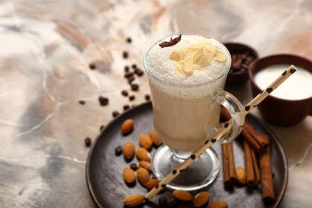 Glass cup of tasty almond latte on grunge background