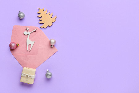 Envelope with Christmas decor and present on lilac backgroundの写真素材