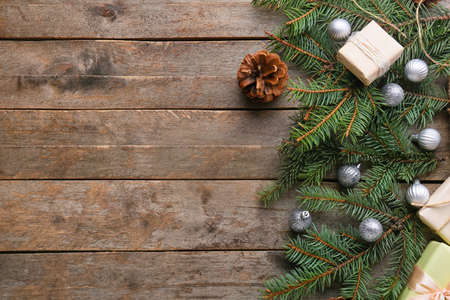 Fir branches with Christmas balls and cone on wooden background