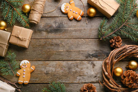 Christmas gifts with fir branches, balls and cookies on wooden background