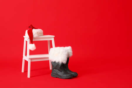 White step stool with Santa hat and boots on red background
