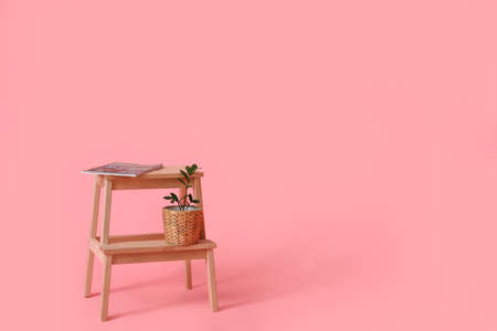 Wooden step stool with magazine and flowerpot on pink backgroundの写真素材