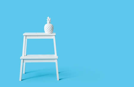 White step stool with decor in shape of pineapple on blue backgroundの写真素材