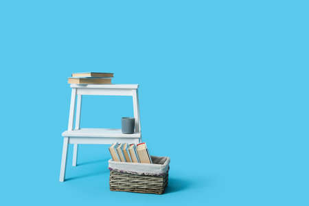 White step stool and basket with books on blue background