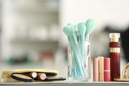Glass with stylish makeup brushes on tableの写真素材