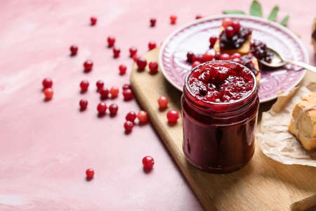 Jar with tasty cranberry jam on table