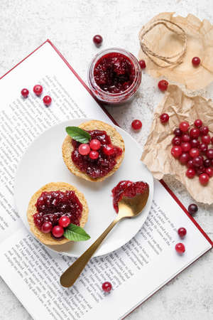 Composition with tasty cranberry jam, sandwiches and berries on white background