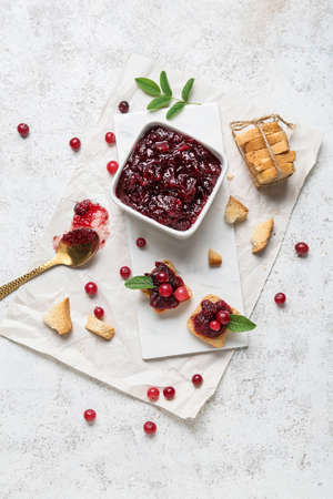 Composition with tasty cranberry jam, bread and fresh berries on white background