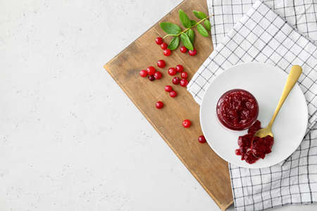 Composition with jar of tasty cranberry jam on light background, closeup