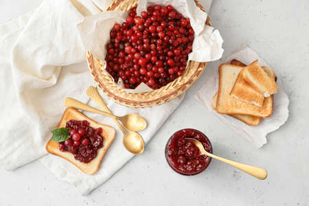Composition with tasty cranberry jam, berries and toasts on light background