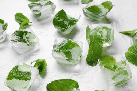 Ice cubes and mint leaves on light background, closeup