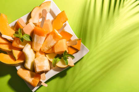 Plate with tasty melon on color background